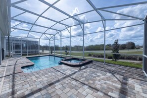 Ein überdachter Pool im Freien mit Pflasterterrasse, umgeben von einer Metallkonstruktion.