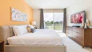 Una habitación de hotel moderna con una cama grande, un televisor de pantalla plana, un balcón con vistas y un cuadro en la pared.
