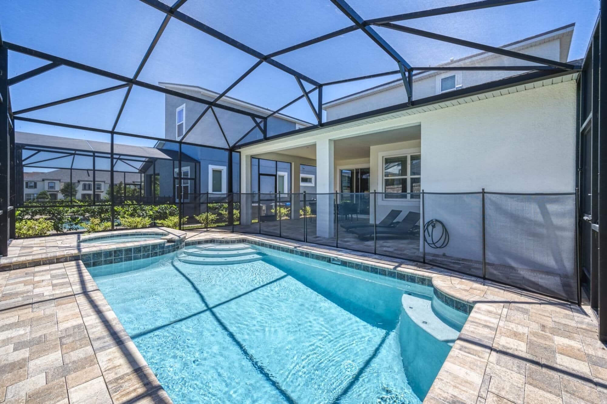Una piscina con cerramiento de vidrio, rodeada por un patio amurallado.