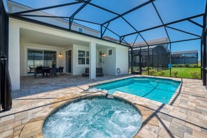 A covered outdoor swimming pool with a hot tub, patio seating, and a view of the surrounding area. - Ultimate Resort Retreat Stunning 6-bedroom Haven (Kissimmee)