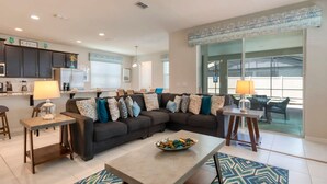 A modern living room with a sectional sofa, a coffee table, and a dining area. - Ultimate Resort Retreat Stunning 6-bedroom Haven (Kissimmee)