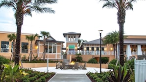 A hotel with a central courtyard featuring a fire pit and outdoor seating, surrounded by palm trees and a well-maintained garden. - Ultimate Resort Retreat Stunning 6-bedroom Haven (Kissimmee)