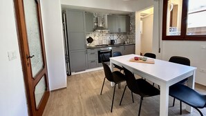 A compact kitchen with grey cabinets, a white countertop, and a dining table with four chairs. - Casa La Pigna in Pisa (Pisa)