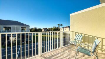 Enjoy the view from this balcony with a metal railing, featuring two comfortable chairs and a tile-covered ground.