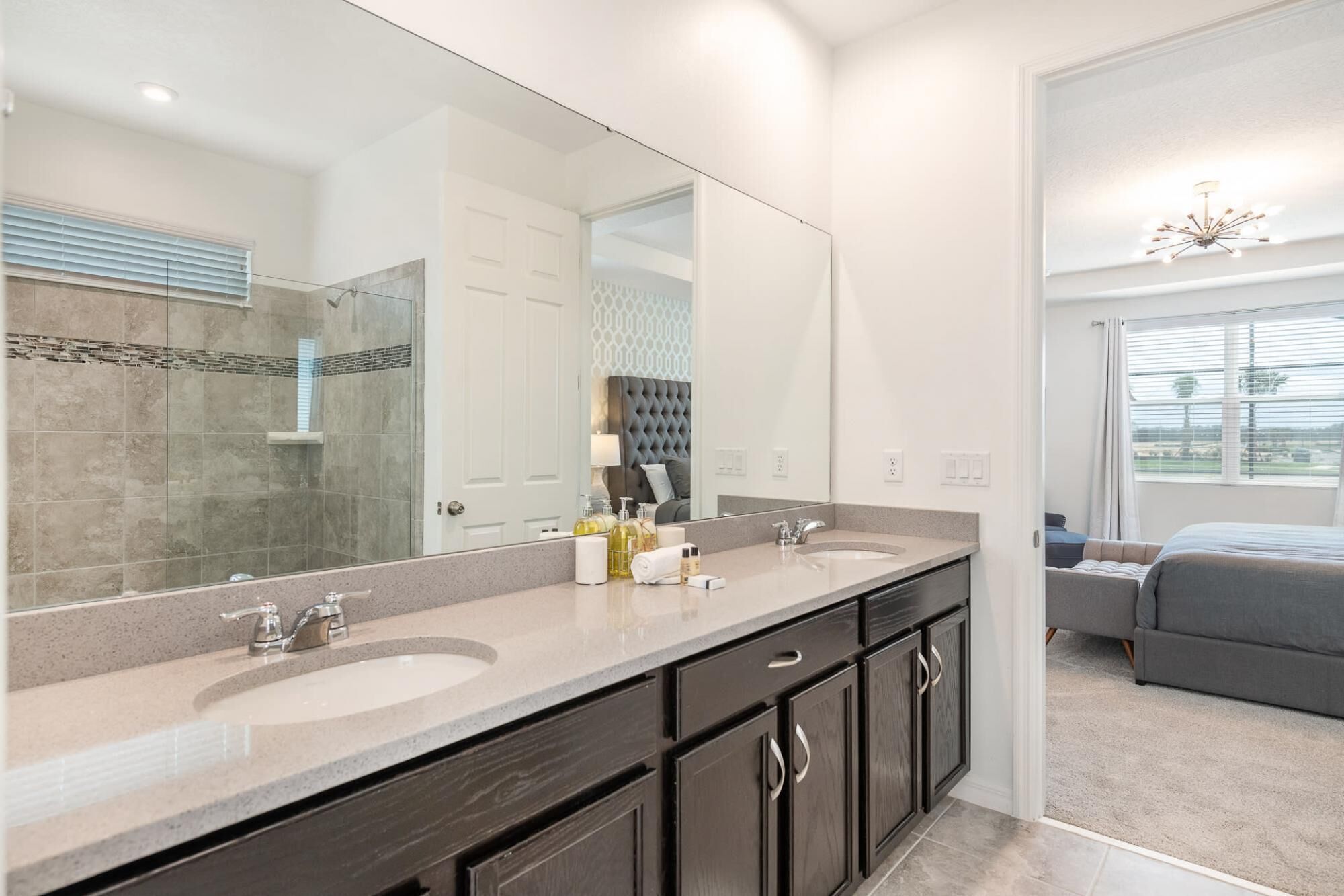 Een moderne badkamer met twee wastafels, een grote spiegel en een douche.