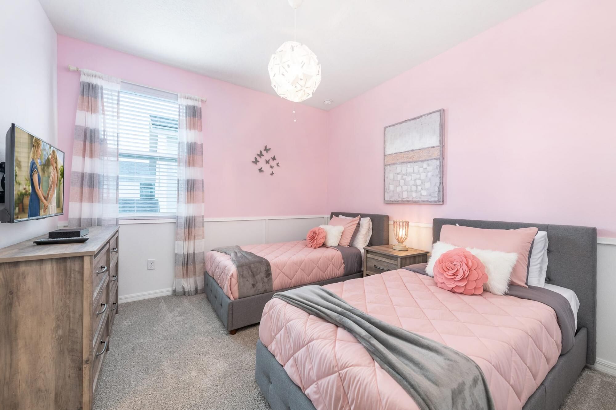 Une chambre avec deux lits, une télévision, un bureau et une fenêtre avec des rideaux.
