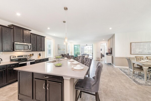 A spacious kitchen with dark wood cabinets, a large island, and a dining area with a long table and chairs.