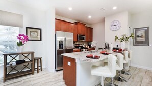 A modern kitchen with wooden cabinets, stainless steel appliances, and a central island with bar stools.