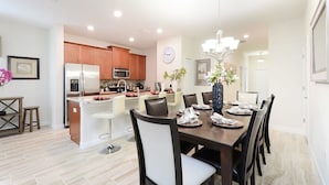 A modern kitchen with a central island, stainless steel appliances, and a dining area with a chandelier.