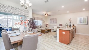 A spacious living area with a dining table, sofas, and a kitchen island. - Private Pool Prime Location Beautiful Home (Kissimmee)