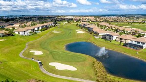 Un parcours de golf avec des bunkers, un étang et des immeubles résidentiels en arrière-plan.