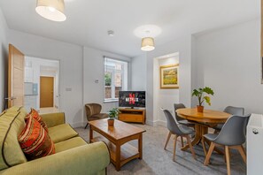 A modern living room with a sofa, coffee table, and a dining area with chairs and a table.