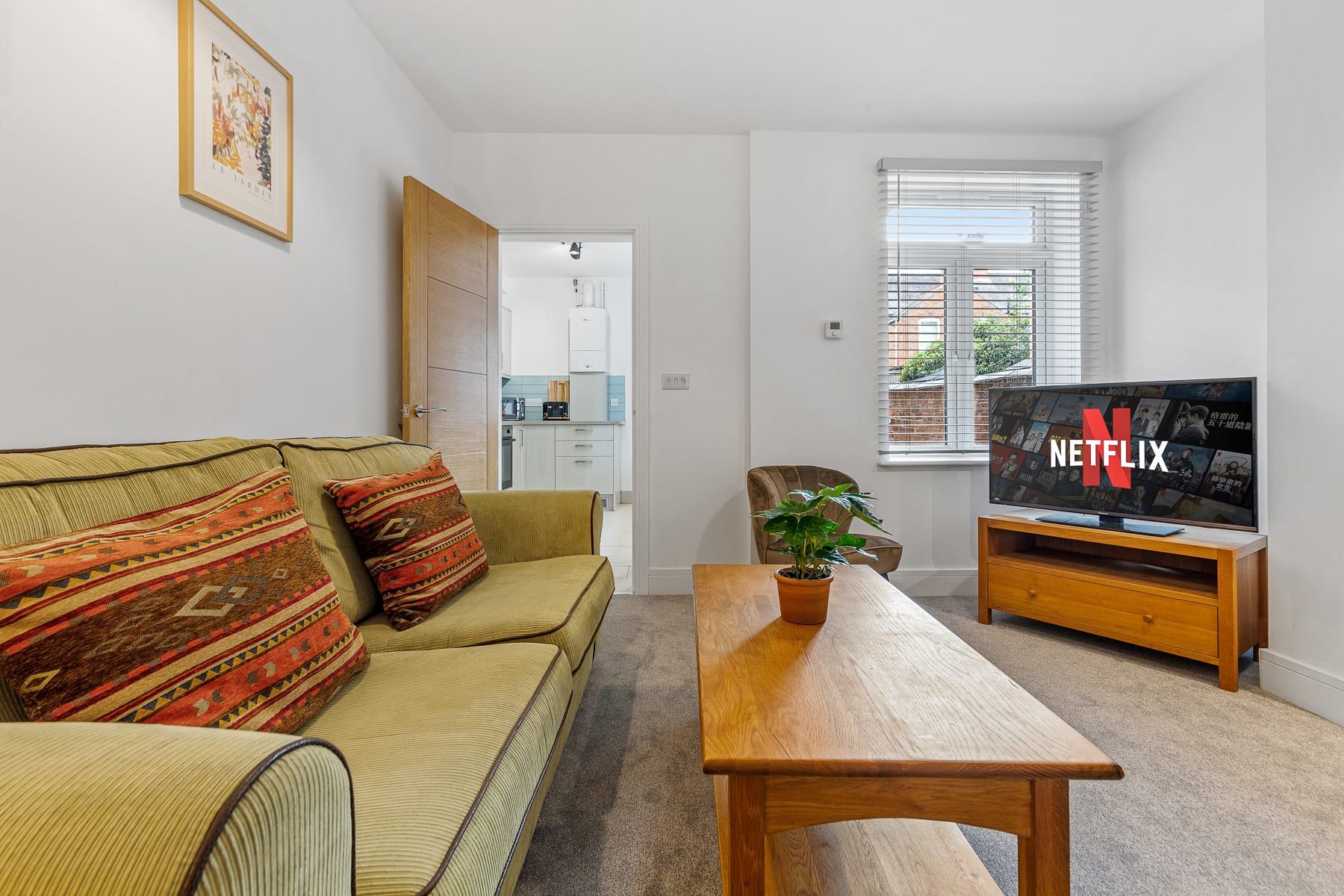 A living room with a sofa, a coffee table, a television, and a potted plant.