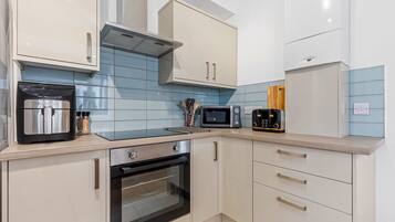 A modern kitchen with a built-in oven, microwave, toaster, and a coffee machine.
