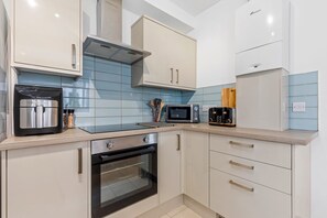A modern kitchen with a built-in oven, microwave, toaster, and a coffee machine.