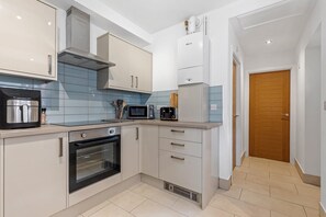 A modern kitchen with a built-in oven, microwave, and coffee maker. - Heathcoat Apartment with Courtyard (Leicestershire)