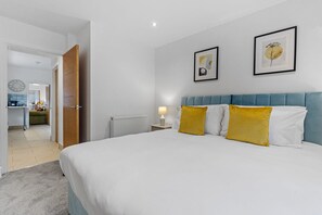 A bedroom with a bed, a nightstand, a lamp, and two framed pictures on the wall.