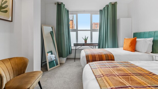 A hotel room with a bed, a chair, a desk, and a window with curtains. - Heathcoat Apartment with Courtyard (Leicestershire)