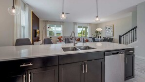 A modern kitchen with a central island, built-in appliances, and pendant lighting. - Champions Gate 8BR Villa-Pool, Game Room, Theater (Four Corners)