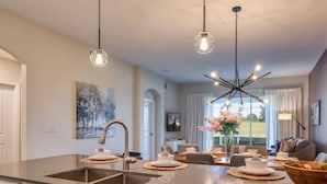 Una cocina moderna con una isla central, electrodomésticos de acero inoxidable, iluminación colgante y un comedor con vistas.
