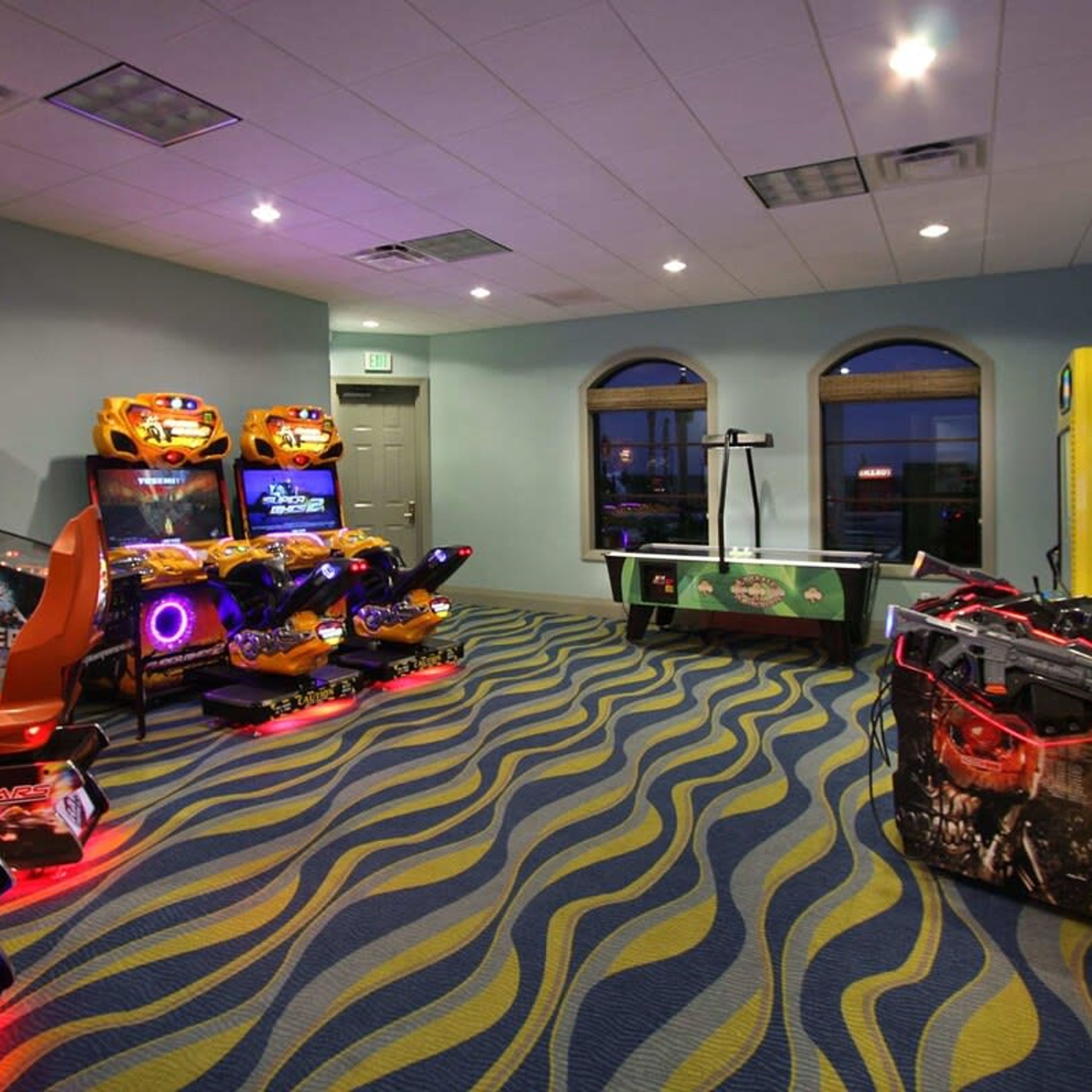 Une pièce équipée de jeux d’arcade, d’une table de billard et d’une grande fenêtre.