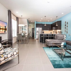 A modern living room with a sofa, a coffee table, and a dining area with a table and chairs. - Serene Villa With Private Pool (Clermont)