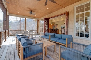 Un espacio de estar al aire libre techado, con mobiliario de madera y ventanas amplias.