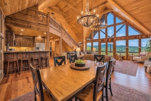 A spacious wooden interior with a dining area, kitchen, and large windows offering a view of the outdoors. - Long-Range Views | Game Room | Fire Pit | Pets (Blue Ridge)
