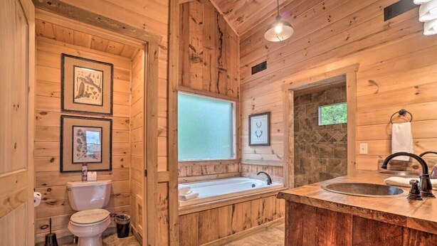 A wooden cabin bathroom with a toilet, sink, and bathtub.