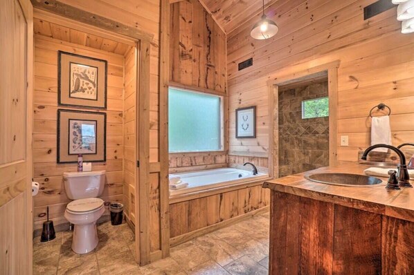 A wooden cabin bathroom with a toilet, sink, and bathtub. - Long-Range Views | Game Room | Fire Pit | Pets (Blue Ridge)