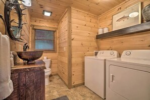 A wooden cabin interior with a wooden toilet, a large wooden bowl sink, and a set of white washing machines. - Long-Range Views | Game Room | Fire Pit | Pets (Blue Ridge)