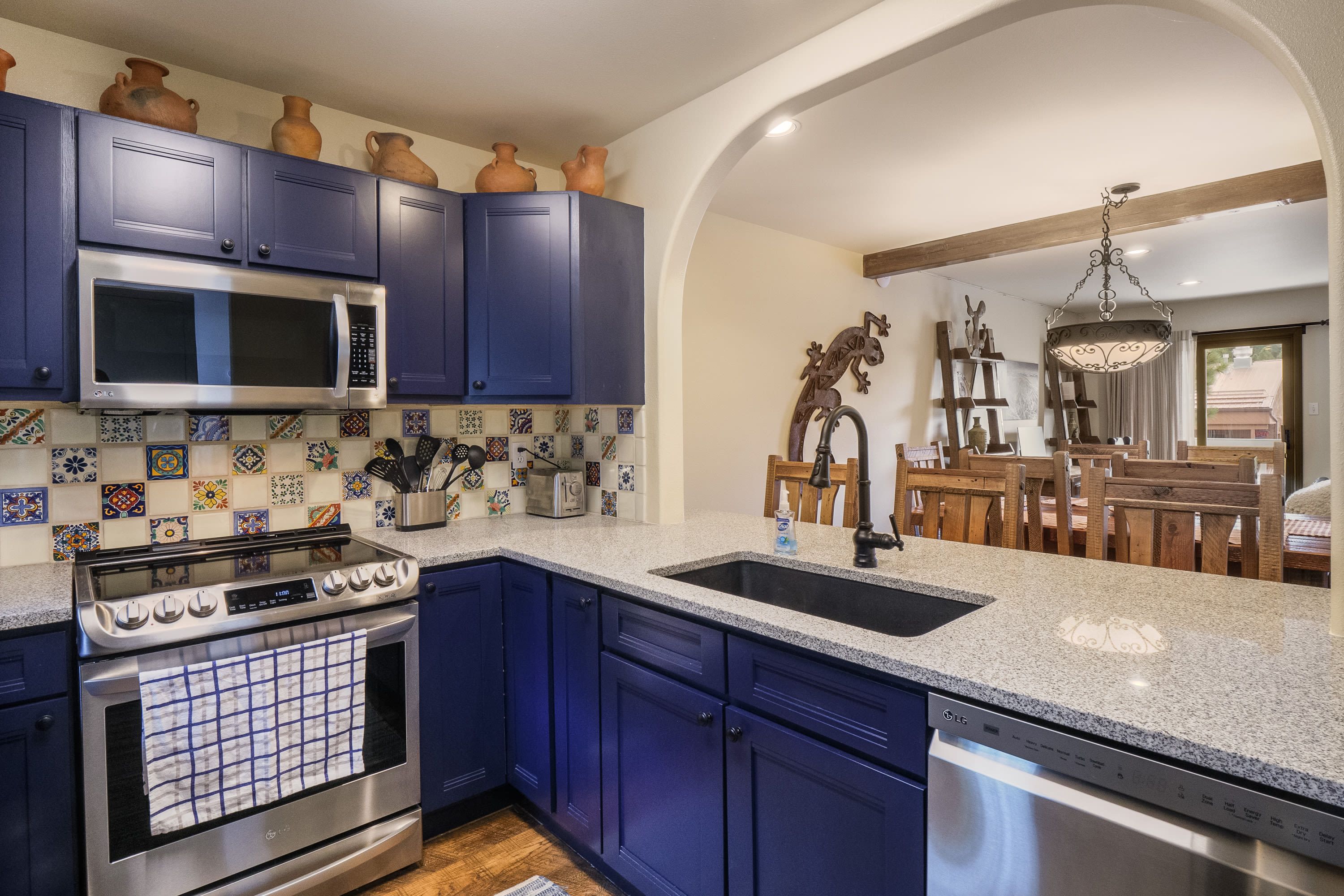 Una cocina con armarios azules, un microondas de acero inoxidable y un lavavajillas.