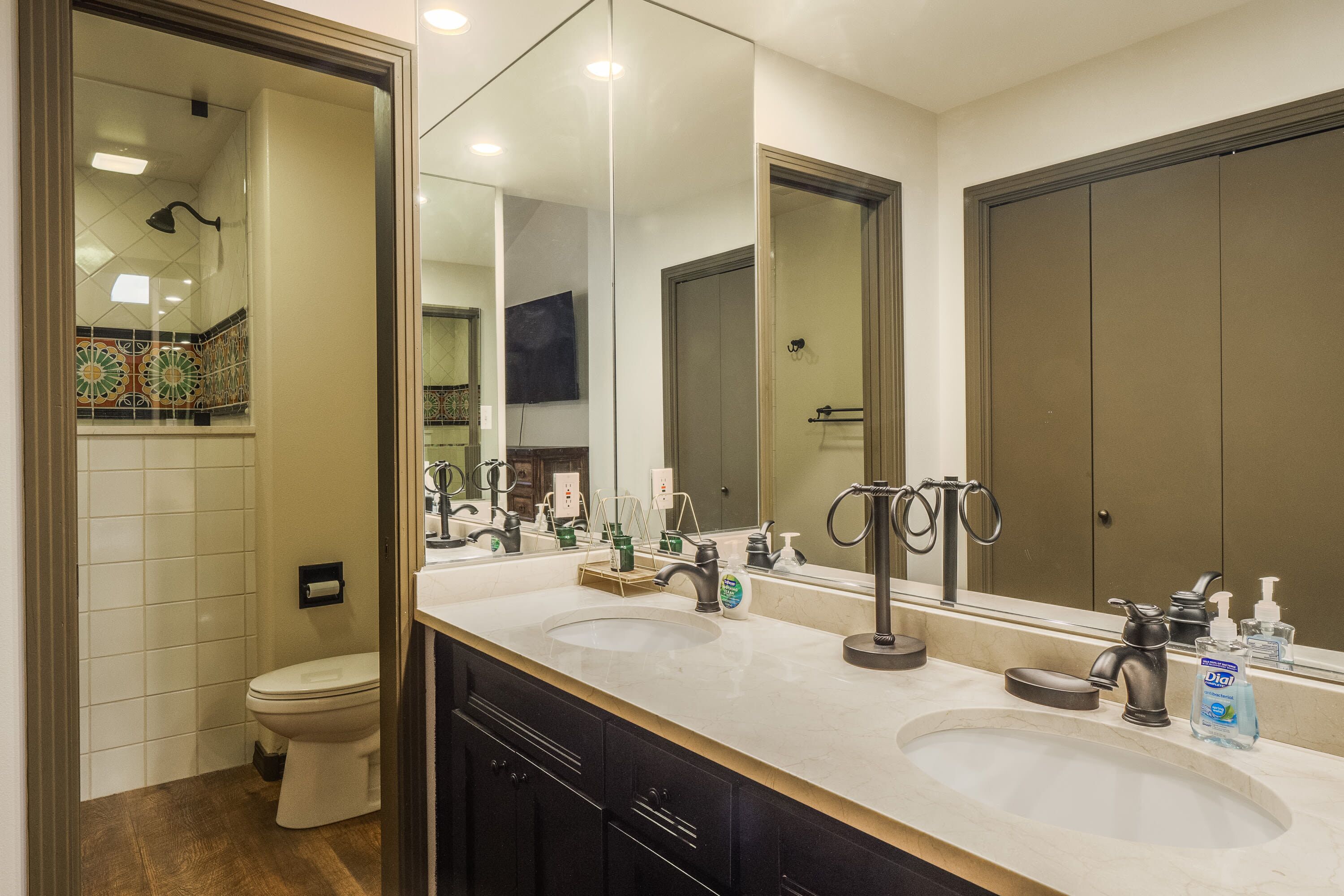 Un baño moderno con dos lavamanos, un espejo grande y un inodoro.