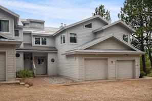 Une maison à deux étages avec un garage, une véranda et une allée gravillonnée.
