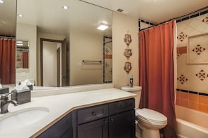 A bathroom with a white sink, dark cabinets, a toilet, and a shower curtain.