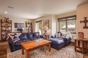 A living room with a dark blue sofa set, a wooden coffee table, and a patterned rug.