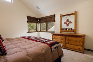 A bedroom with a bed, a dresser, a window with blinds, and a wall decoration.