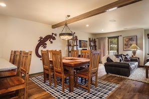 A dining area with a wooden table and chairs, a chandelier, and a checkered rug.