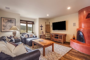A living room with a fireplace, a sofa set, a coffee table, and a television mounted on the wall.