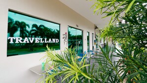 A travel agency interior with a large window displaying 'TRAVELLAND' and a view of palm trees. - Travelland Hotel (Ipoh)