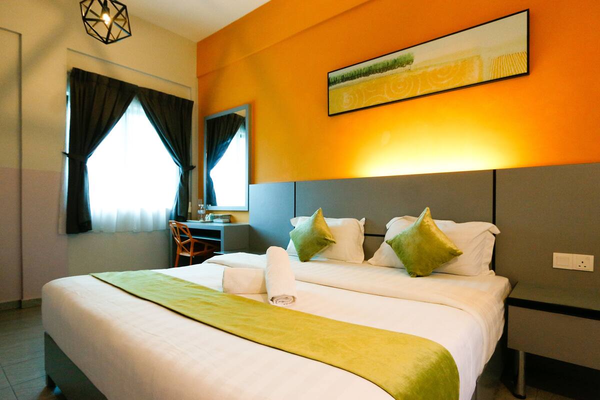A hotel room with a large bed, a desk, and a chair.