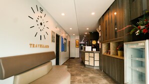 A hotel lobby with a reception desk, a clock on the wall, a bench, and a refrigerator. - Travelland Hotel (Ipoh)