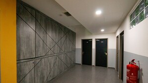 A hallway with a modern wall design, two doors labeled 101 and 102, and a red fire extinguisher mounted on the wall. - Travelland Hotel (Ipoh)