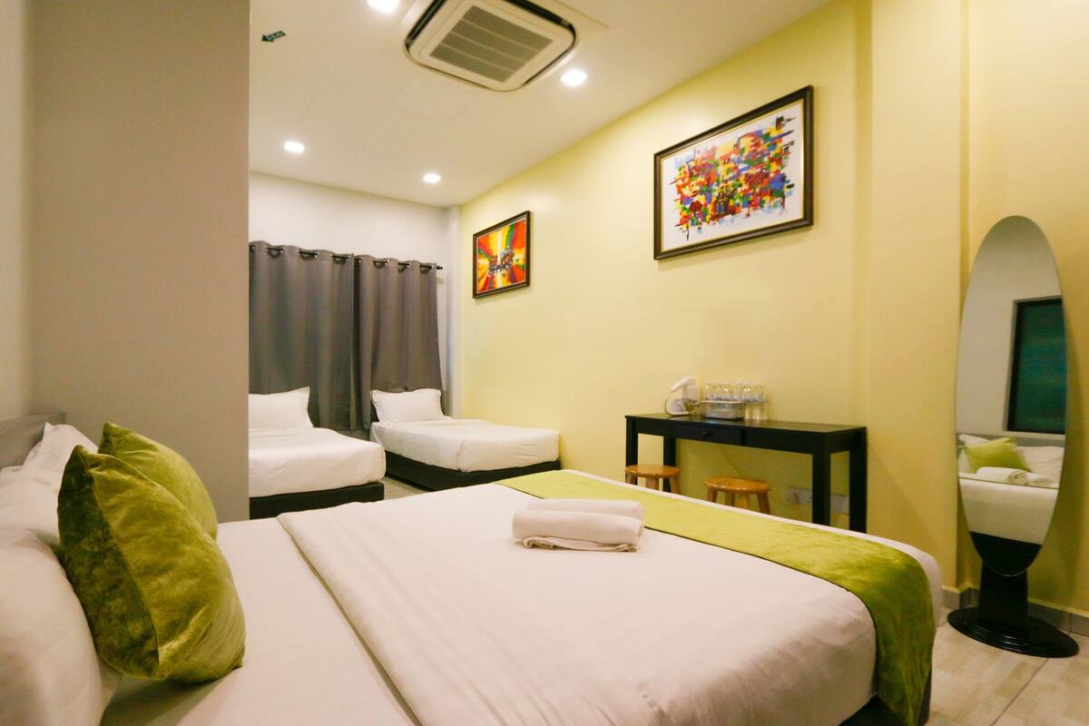 A hotel room with two beds, a desk, a chair, a mirror, and artwork on the walls.