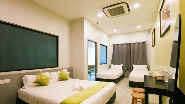 A hotel room with two beds, a desk, a chair, a TV, and a bathroom with a shower curtain. - Travelland Hotel (Ipoh)