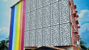 Un edificio con un panel vertical de colores de arcoíris, fachada decorada y una pequeña piscina al aire libre.