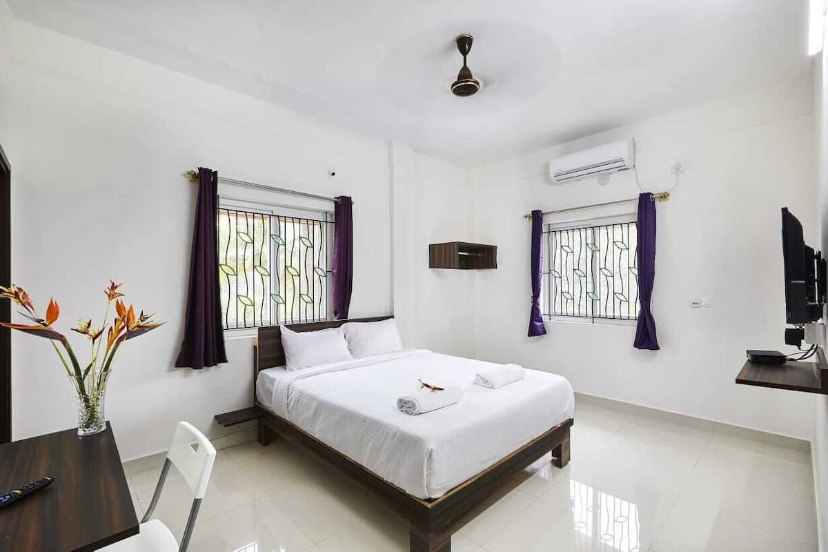 A hotel room with a bed, a desk, a chair, a TV, and a ceiling fan.