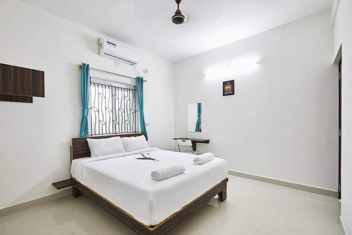 A neatly arranged bedroom with a bed, bedside table, and a mirror.