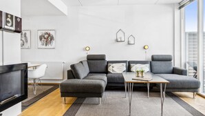 A modern living room with a sectional sofa, a flat-screen TV, and a dining table.