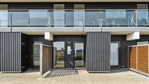 A modern building with a glass balcony, a door labeled '50', and a metal gate.